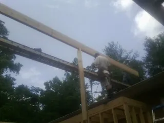 Carpenter setting a ridge beam over a new addition frame — Ice Dam Removal by Roofing Brothers in Troutman