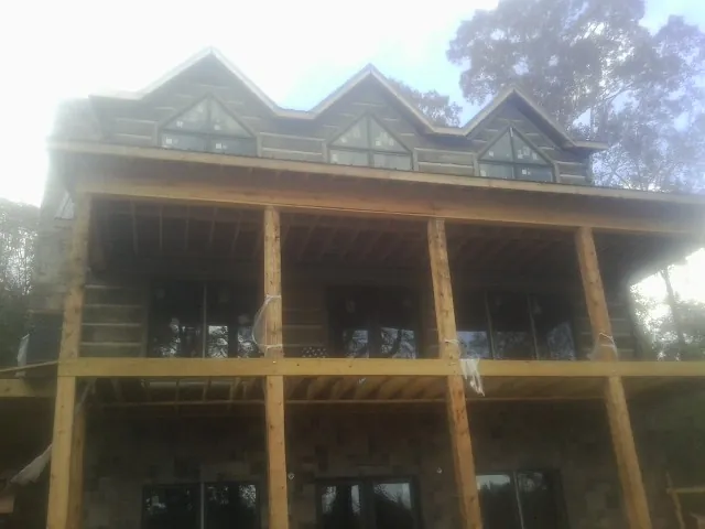 Dormers and porch framing on a large log home under construction — Roof Coating work by our crew in Troutman