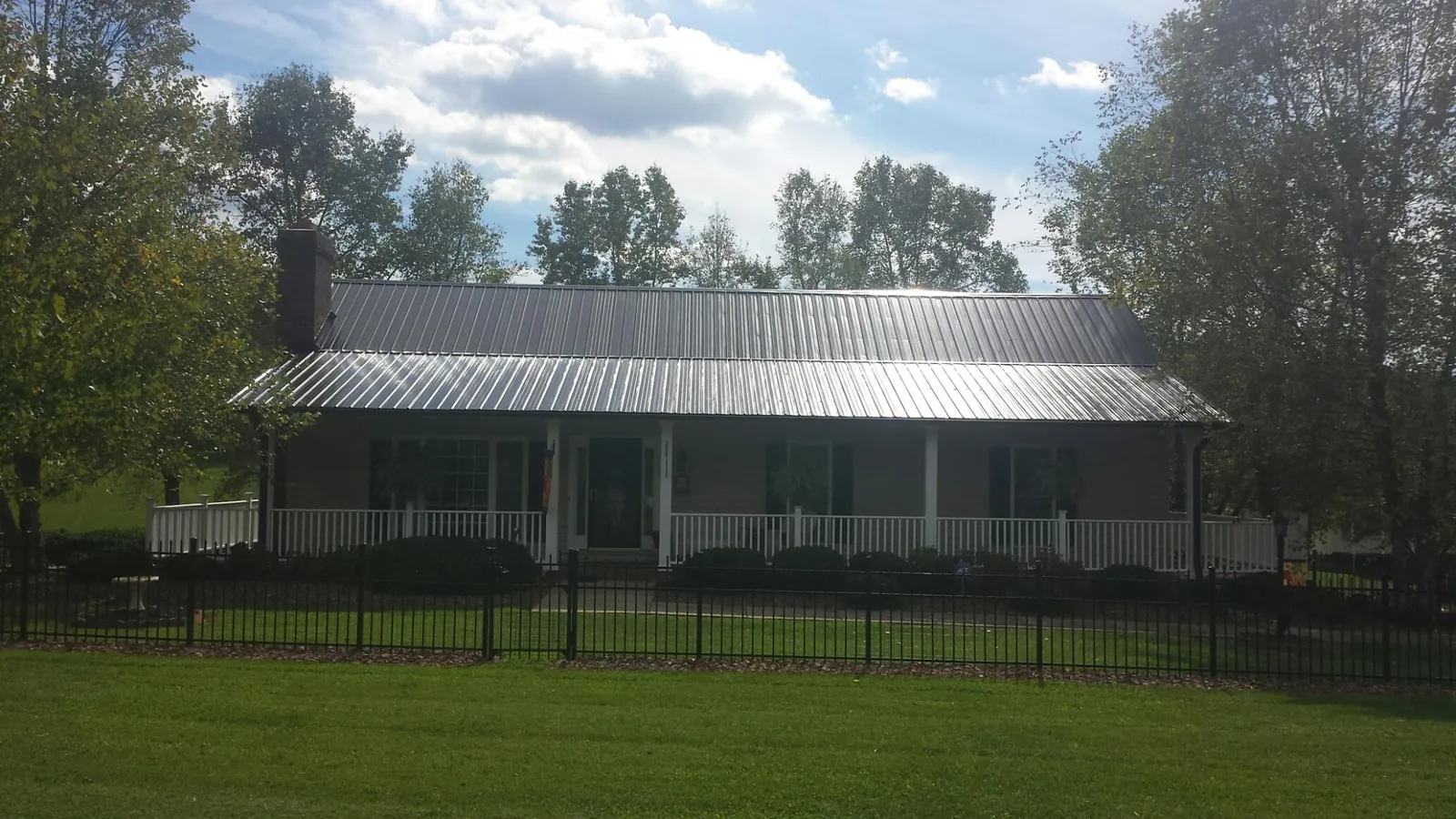 Gray metal roof on a brick ranch with a full width front porch — Gutter Guard Installation work by our crew in Troutman