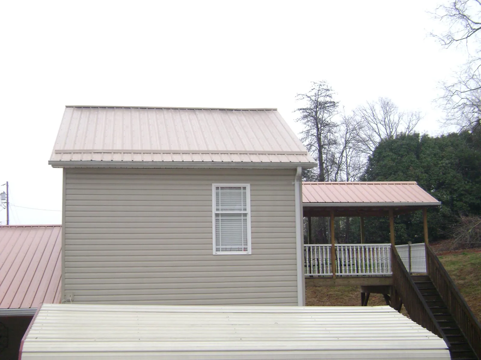 Tan metal roofs on a two story addition and attached porch, from a Roof Replacement job in Troutman