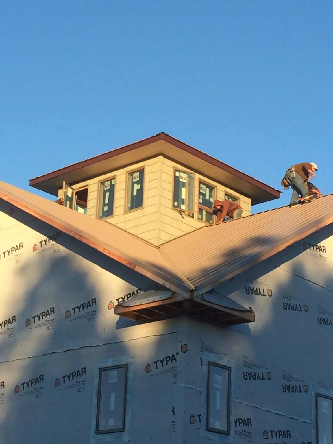 Roofers working around a rooftop cupola on a new metal roof at sunset — Roof Waterproofing in Troutman by Roofing Brothers